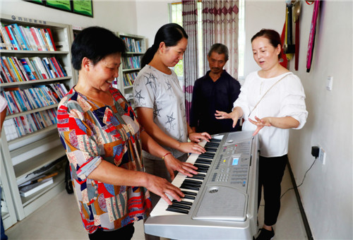 廣安市廣安區(qū)興平鎮(zhèn)的六合村文化活動室，來自區(qū)文廣旅局的駐村幫扶干部正在指導(dǎo)村民彈電子琴，豐富村民的文化生活.jpg